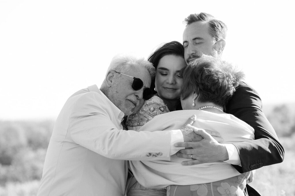 Bride and groom share a candid emotional group hug with their family on their wedding day in New York. 