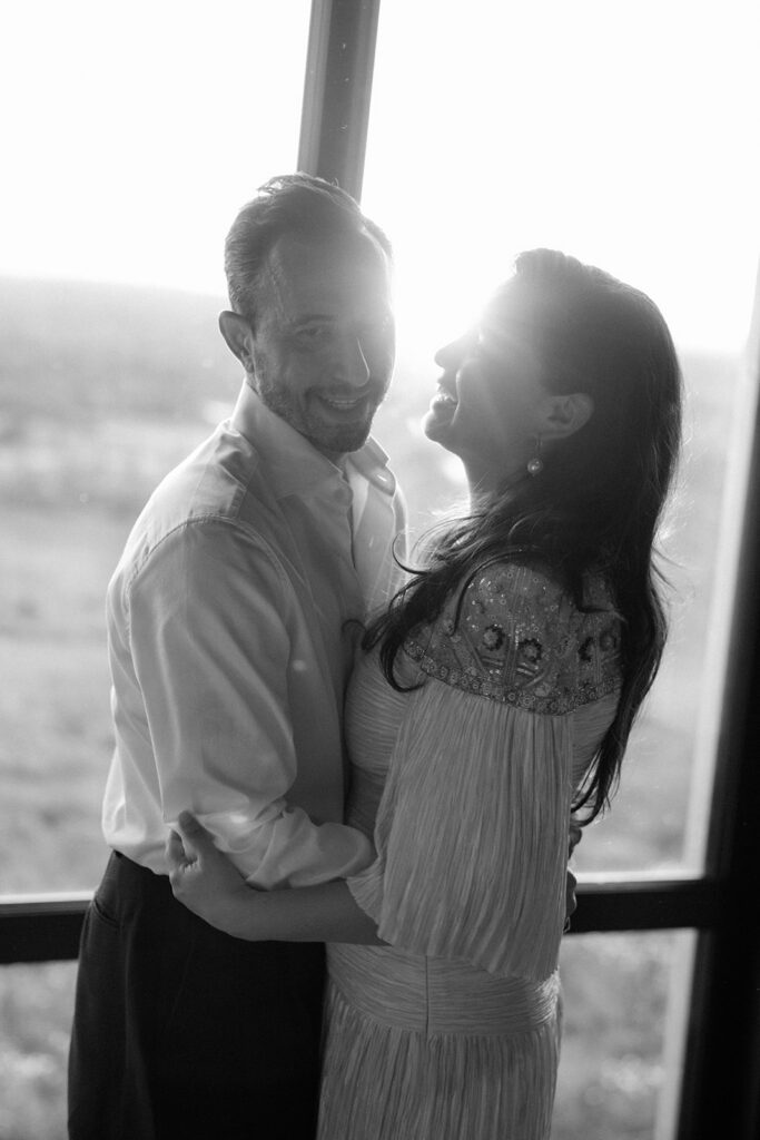 Bride and groom laugh together while dancing as the sun sets over the Hudson Valley in the background. 