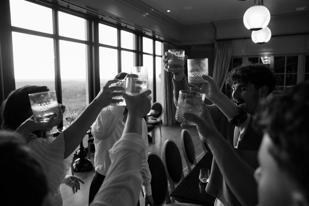 Wedding party cheers their glasses together during a candid moment of celebration.