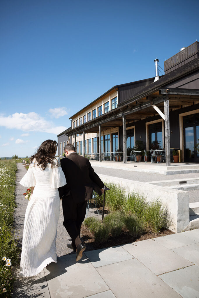 Couple joins hands while walking into the Klocke Estate brewery for their wedding ceremony. 